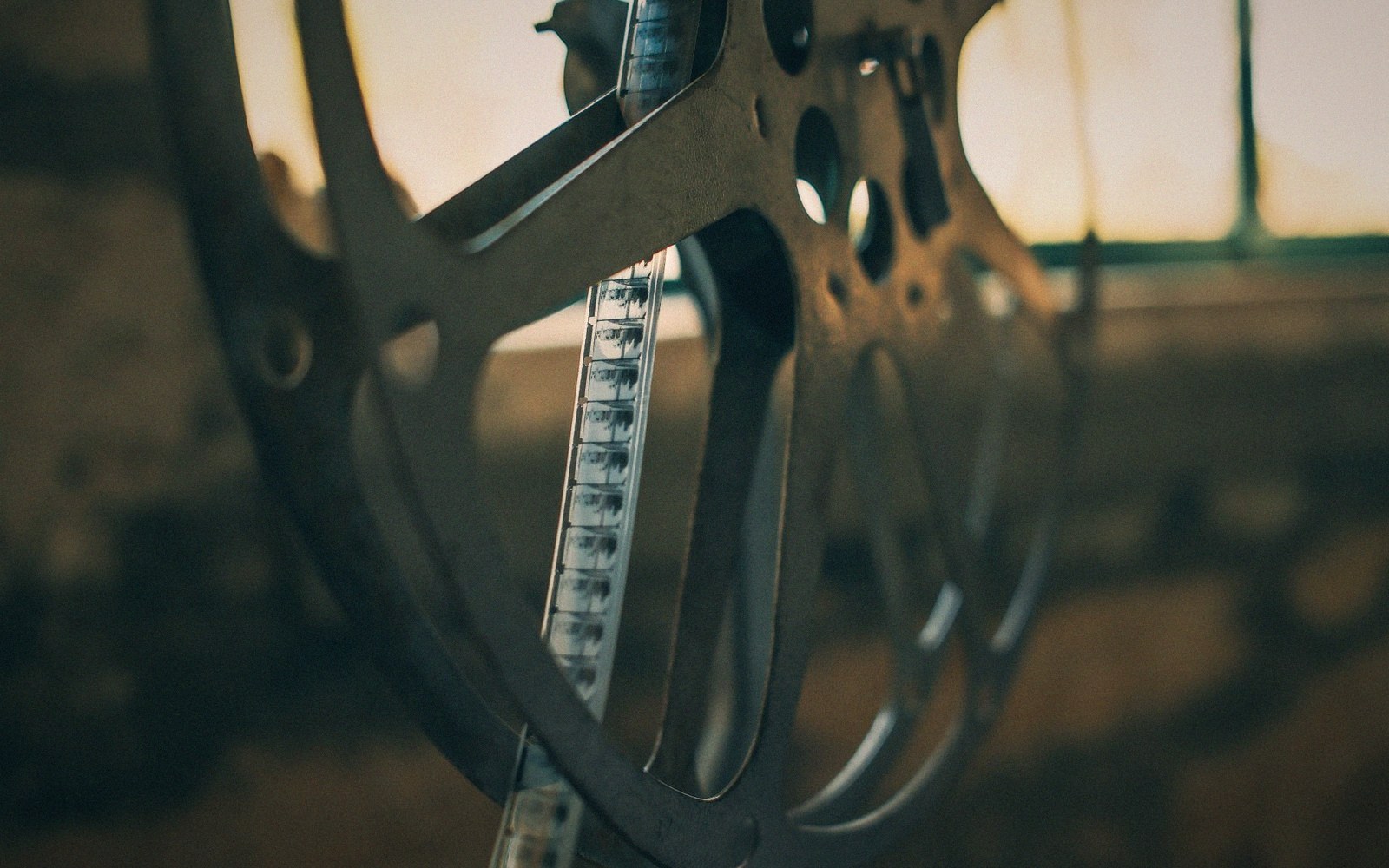 Close-up of a metal film reel with celluloid strip threaded through its spokes