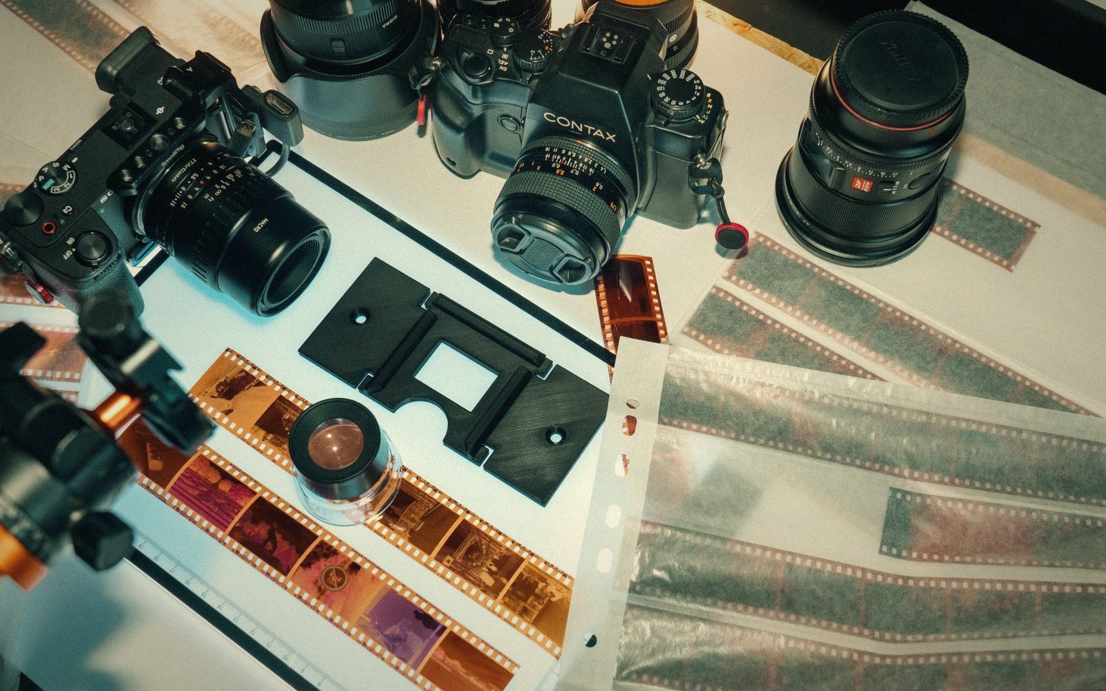 Cameras, lenses and film strips laid out on a table for digitizing negatives
