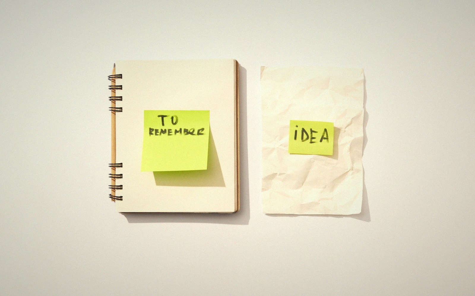 Sticky notes reading "to remember" and "idea" attached to a notebook and crumpled paper